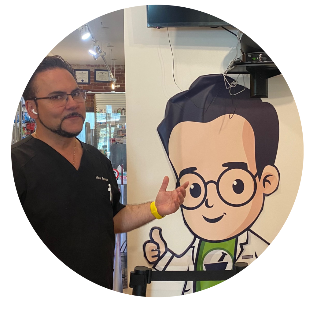 MisterPharmacist_Toronto_Online_Pharmacy A man in a black shirt stands beside a large cartoon drawing of a character wearing glasses and a lab coat. Gesturing towards the cartoon, he seems to promote TorontoOnlinePharmacy, where fast prescription delivery is just part of the service, as evident from the certificates adorning the indoor space.