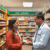 Pharmacist assisting a smiling customer in a bright, modern pharmacy with shelves of health products and clear signage about minor ailments.