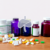 Illustration of medication bottles and pills on a wooden table with a faint human liver icon overlay, symbolizing drug metabolism and medication sa...
