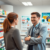 A friendly pharmacist consulting with a patient in a bright, modern pharmacy surrounded by medicine shelves and health posters about cold and flu a...