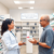 Modern pharmacy interior with a pharmacist consulting a customer about skincare, visible products, and a sign for pharmacist services on minor ailm...