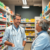 A modern pharmacy with a pharmacist consulting a patient, surrounded by shelves of medications and nasal congestion relief products.