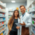A pharmacist consulting with a patient in a modern pharmacy filled with shelves of medications and healthcare products.