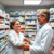 Bright community pharmacy interior with a pharmacist assisting a patient near shelves of eye care products and medications, highlighting profession...