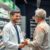 Pharmacist consulting a patient about back pain medication in a bright, modern pharmacy with shelves of medicines and healthcare products.