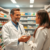 Pharmacist consulting a patient in a modern pharmacy, holding medication with shelves of medicines in the background, symbolizing accessible health...