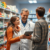 Pharmacist consulting a patient using a digital tablet in a modern pharmacy with shelves of medicines and health products.