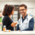 Pharmacist consulting patient in modern pharmacy, holding prescription medication with healthcare symbols like stethoscope and medicine bottles nea...