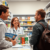 Pharmacist consulting traveler in modern pharmacy with travel health brochures and malaria prevention products on the counter.
