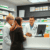 A modern pharmacy counter with a pharmacist consulting a patient, shelves of medication visible in the background.