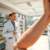 Close-up of an arm with a mild sun rash, a pharmacist in a white coat offering advice inside a bright, modern pharmacy.